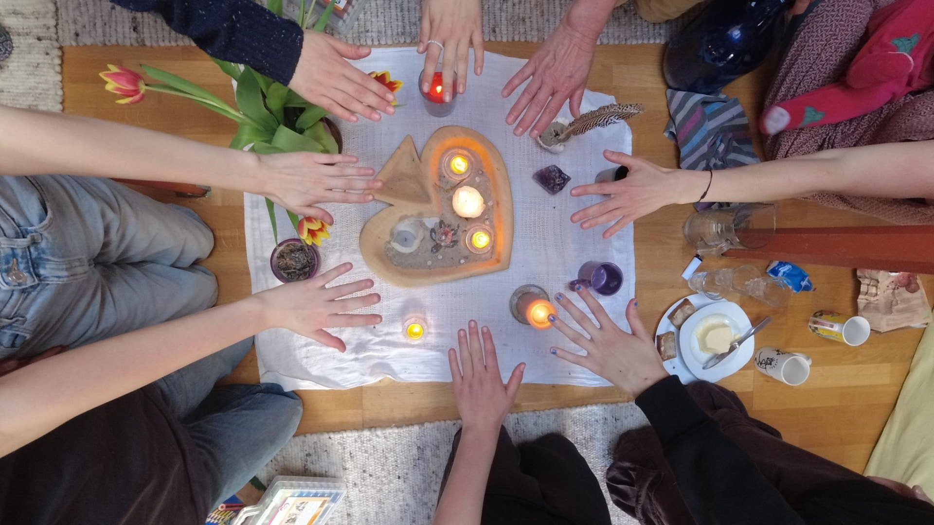 Mädchenkreis mit Händen um Kerzen in Herzform – Gemeinschaft und Rituale